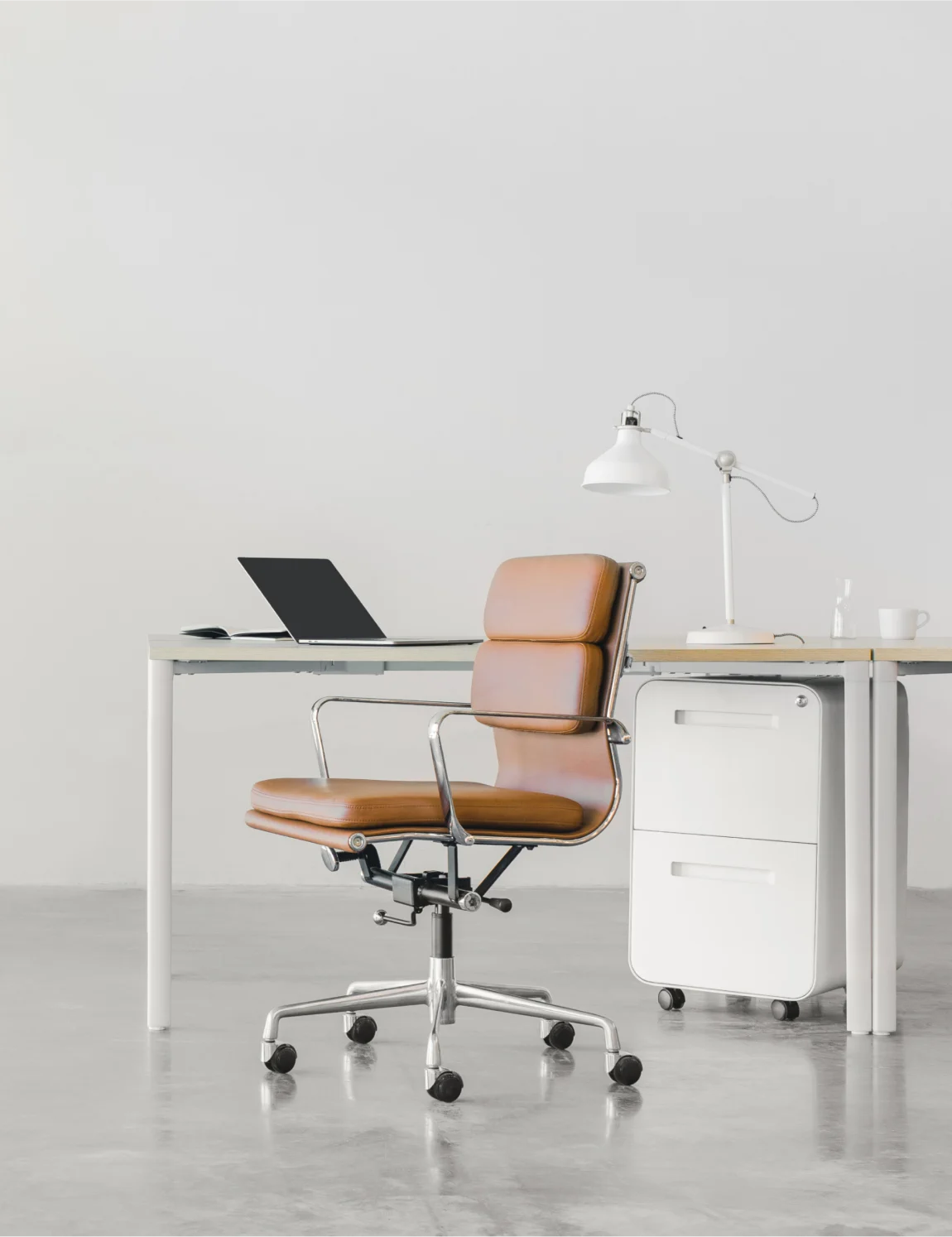 Brown leather chair in front of an office desk in a white room.